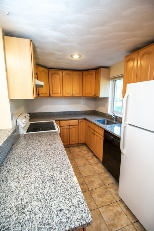 58 Bishop Drive, Unit 58 Framingham, MA 01702 - Photo 5 of 13 a kitchen with granite countertop a refrigerator and a stove top oven