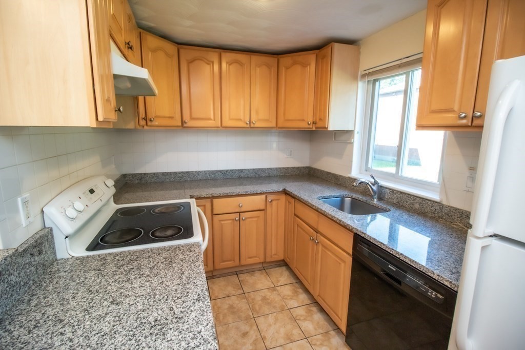 58 Bishop Drive, Unit 58 Framingham, MA 01702 - Photo 6 of 13 a kitchen with granite countertop a sink a stove top oven and cabinetry