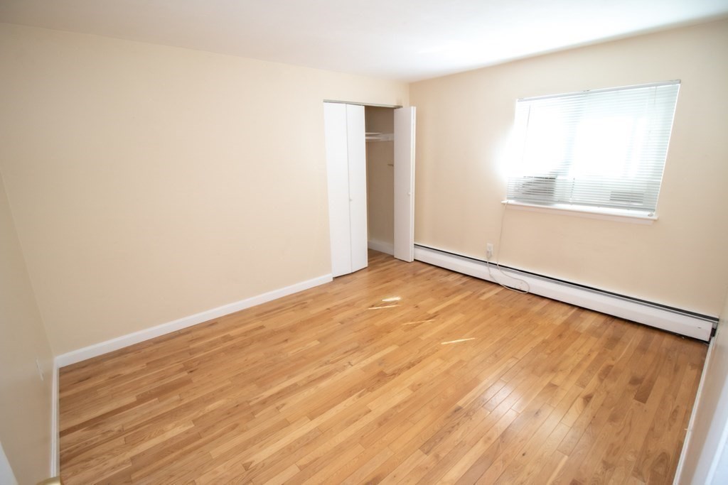 58 Bishop Drive, Unit 58 Framingham, MA 01702 - Photo 9 of 13 an empty room with wooden floor and windows