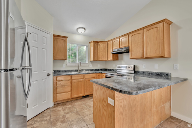 1118 North Ridge Court Spanish Fork, UT 84660 - Photo 11 of 32 Kitchen featuring stainless steel appliances, a peninsula, vaulted ceiling, dark countertops, and light tile patterned floors