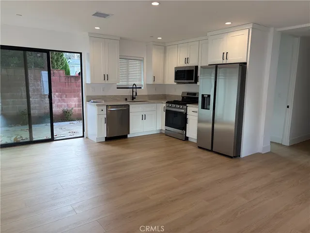 a kitchen with granite countertop a refrigerator and a stove top oven