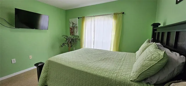 a bed sitting in a bedroom next to a window and a potted plant