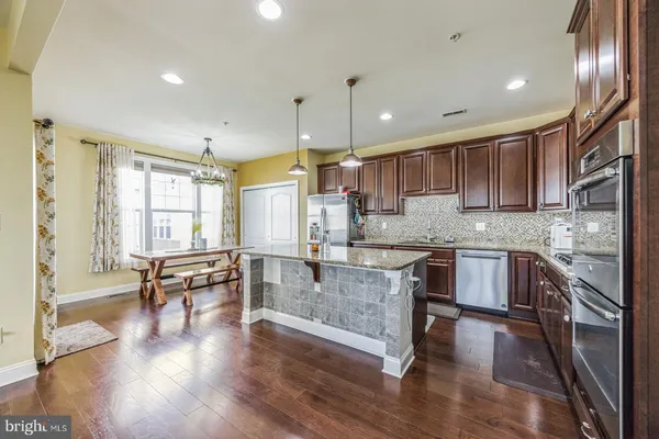 a kitchen with stainless steel appliances granite countertop wooden floors stove top oven and sink