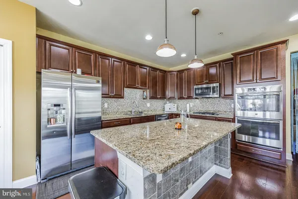 a kitchen with kitchen island granite countertop a sink a counter space appliances and cabinets