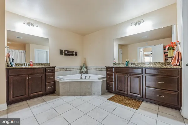 a spacious bathroom with a granite countertop sink a mirror and a bathtub