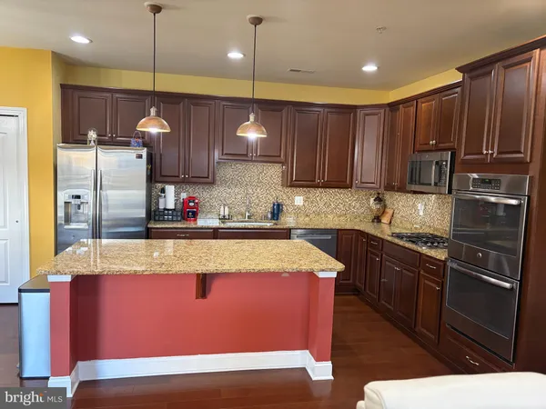 a kitchen with kitchen island granite countertop wooden cabinets and stainless steel appliances