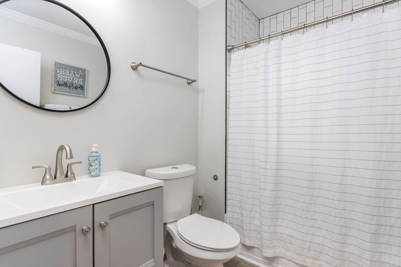 1415 Berkeley Street Durham, NC 27705 - Photo 15 of 24 a bathroom with a toilet a sink a mirror and shower curtain