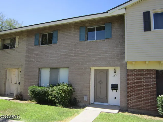 a brick house that has a small yard and a large window