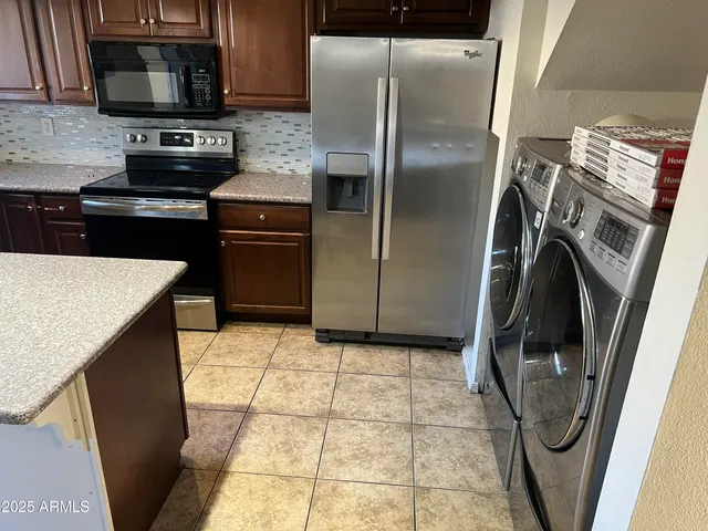 a kitchen with granite countertop a refrigerator and a stove top oven