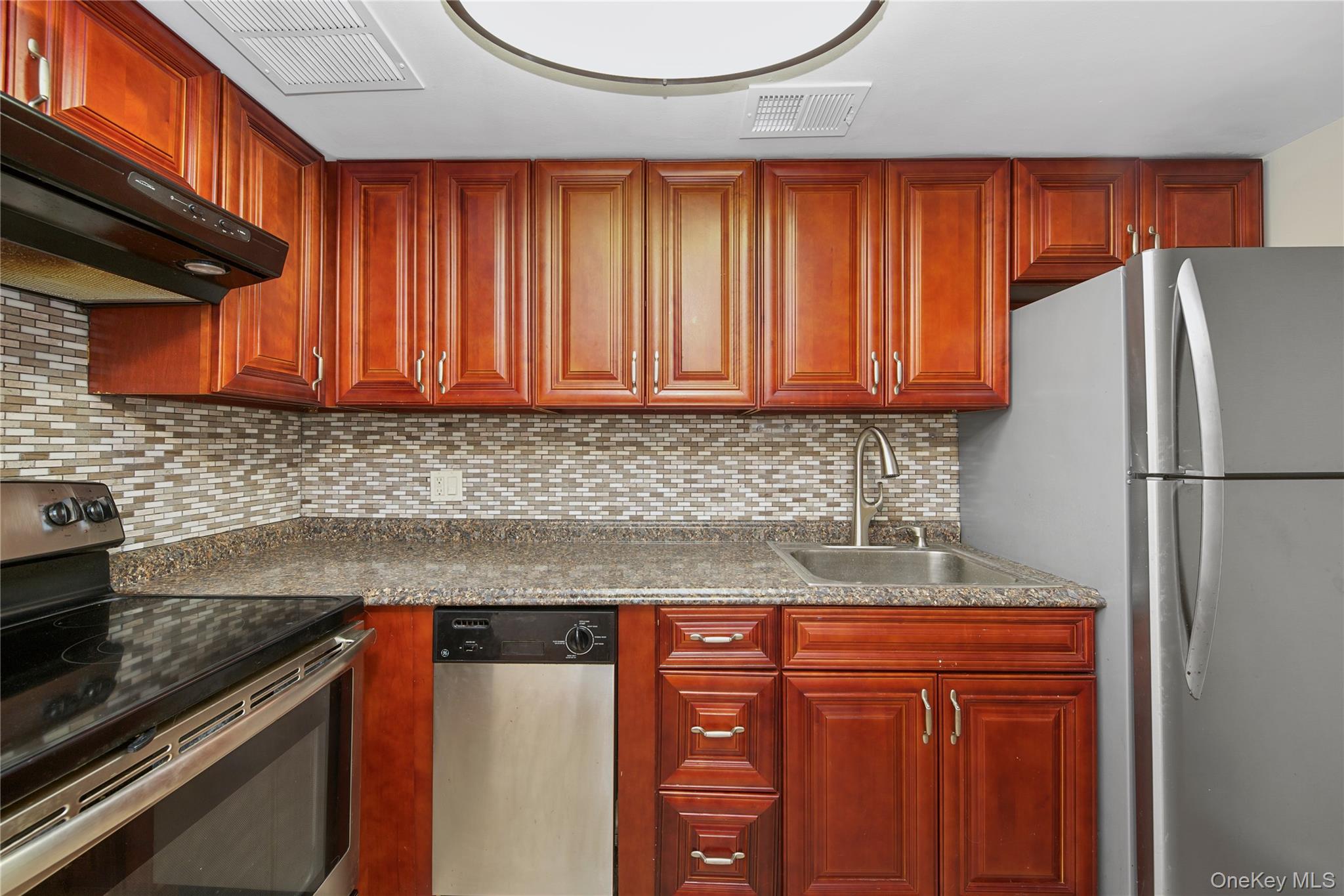 305 Chateau Rive, Unit 305 Peekskill, NY 10566 - Photo 12 of 22 Kitchen with appliances with stainless steel finishes, backsplash, dark brown cabinets, and ventilation hood