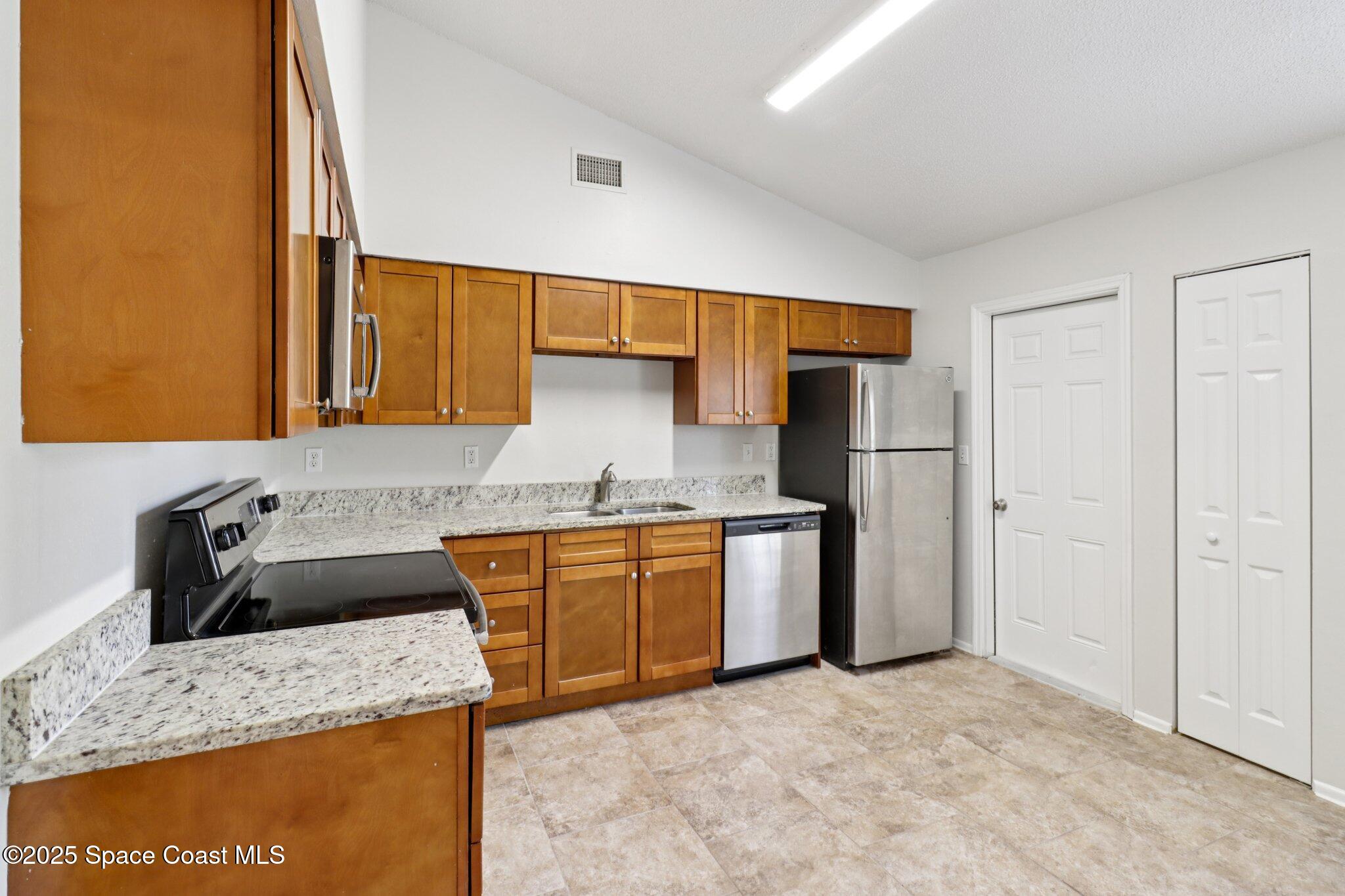 5215 Holden Road Cocoa, FL 32927 - Photo 15 of 34 a kitchen with stainless steel appliances granite countertop a sink stove and refrigerator