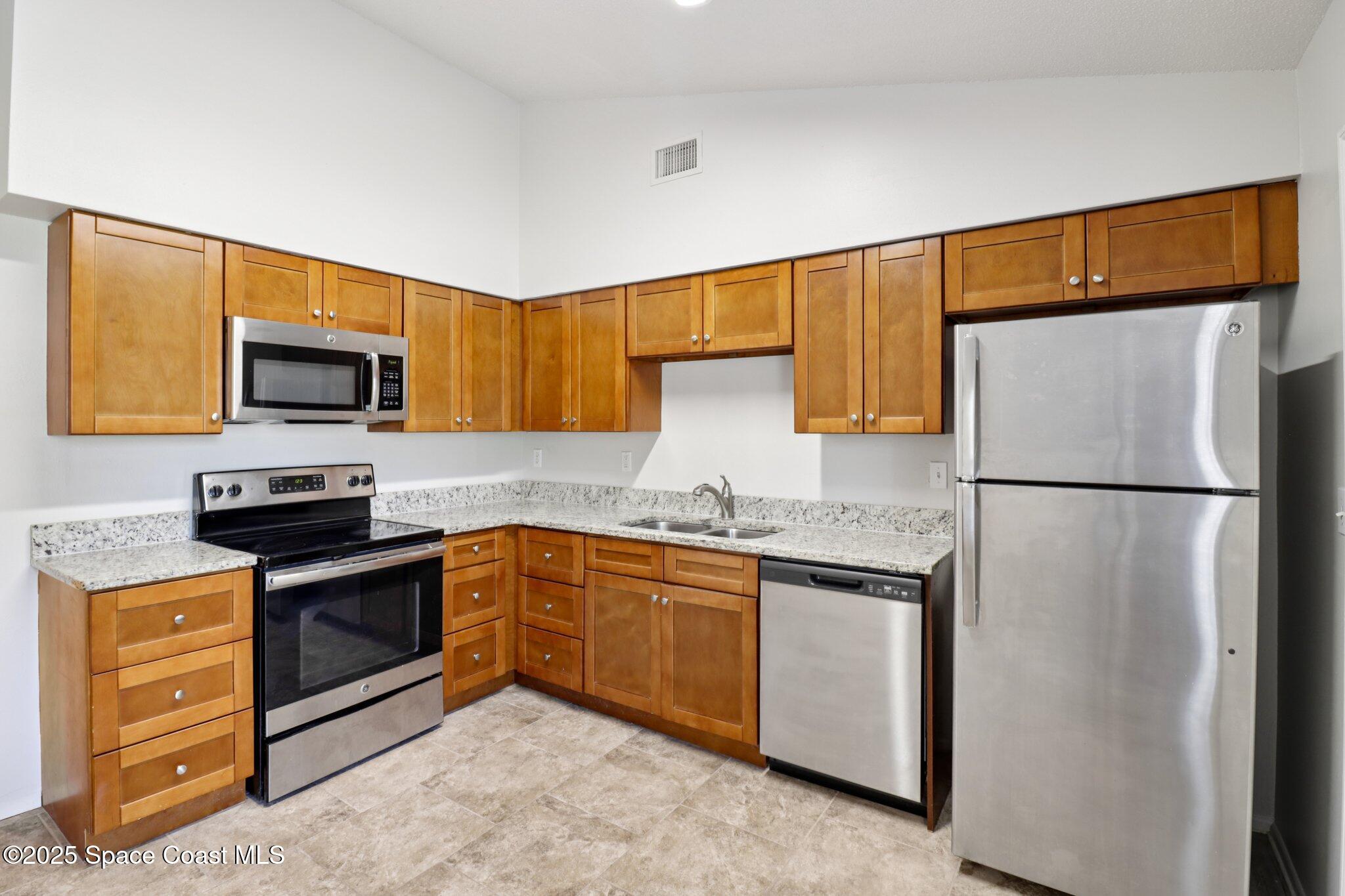 5215 Holden Road Cocoa, FL 32927 - Photo 16 of 34 a kitchen with stainless steel appliances granite countertop a refrigerator sink stove and microwave
