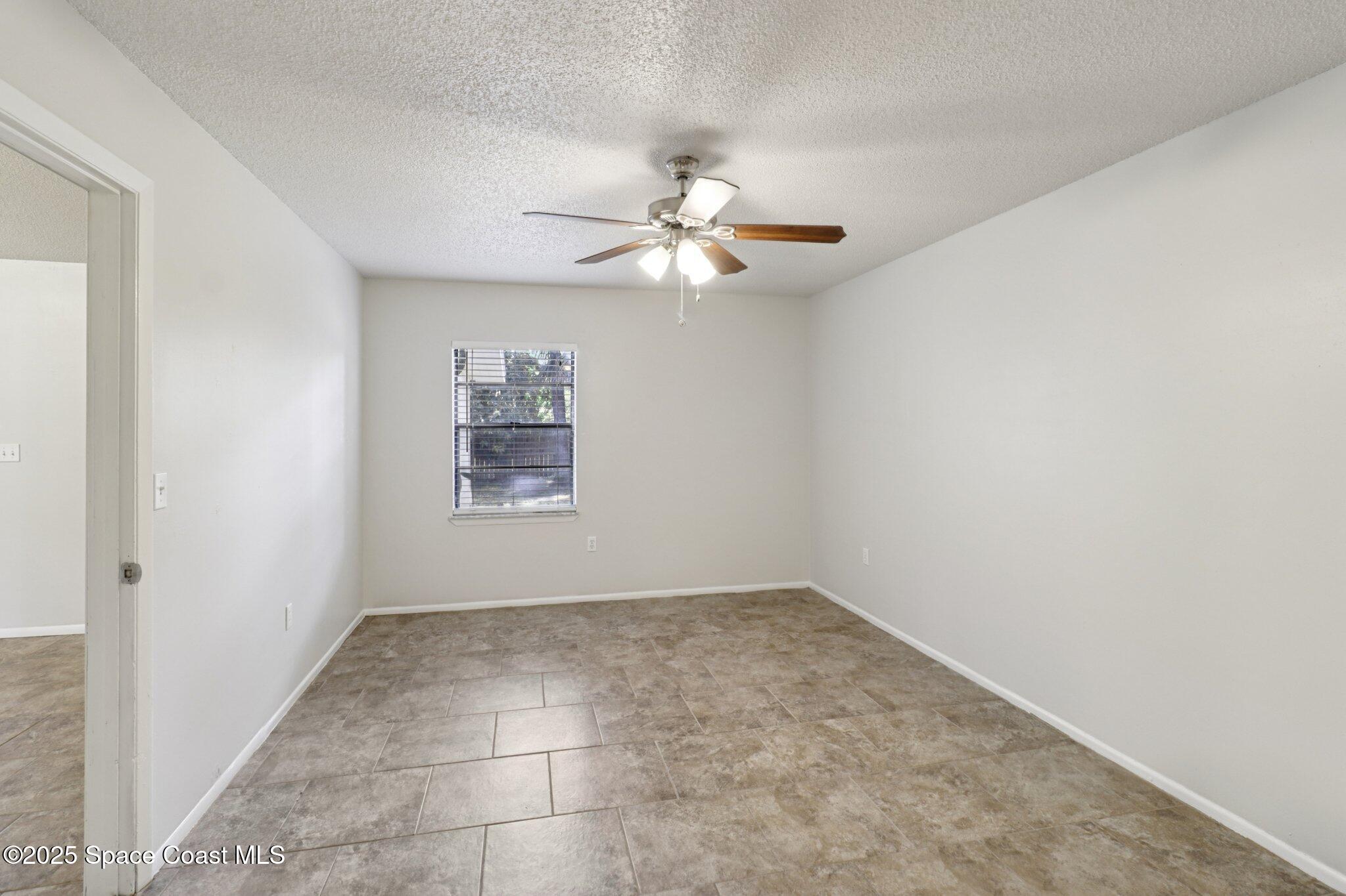 5215 Holden Road Cocoa, FL 32927 - Photo 20 of 34 a view of an empty room with a ceiling fan and a window