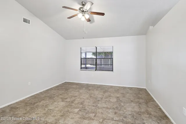 an empty room with windows and fan