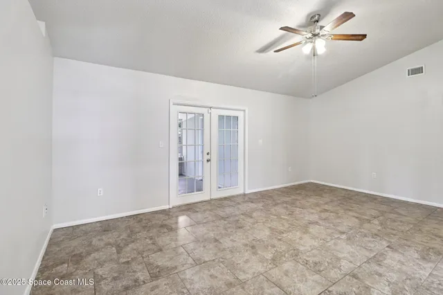 a view of an empty room with a chandelier fan