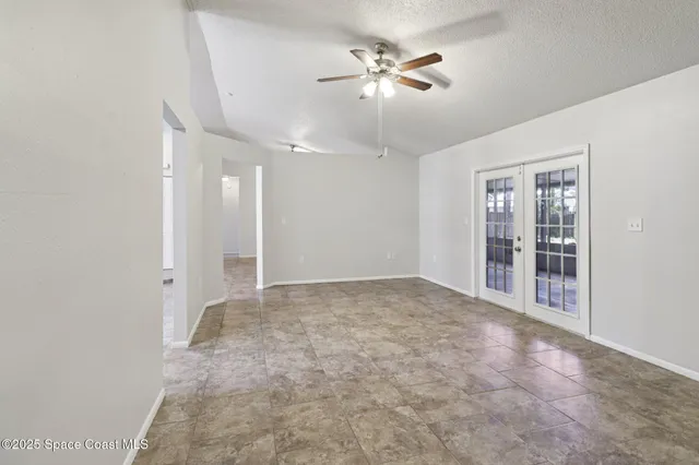 wooden floor in an empty room with a chandelier fan
