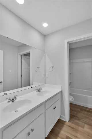 a bathroom with a double vanity sink and mirror with wooden floor
