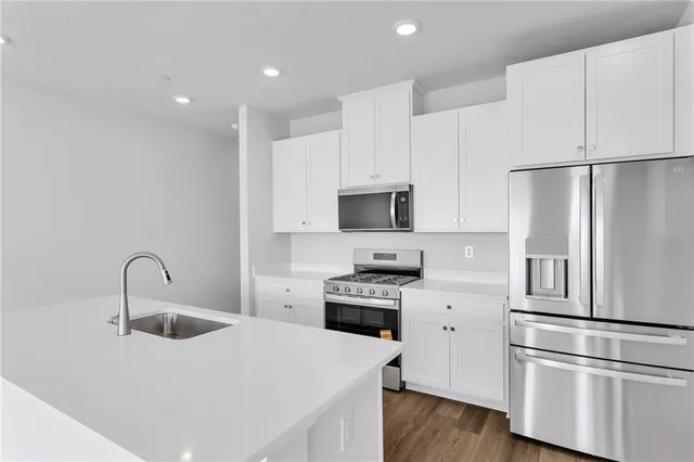 a kitchen with stainless steel appliances a refrigerator stove and white cabinets