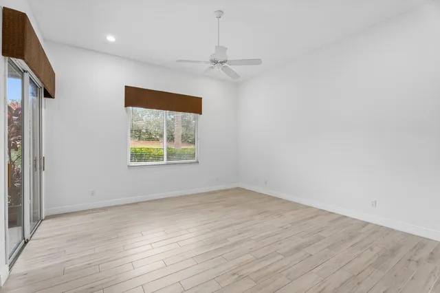 an empty room with wooden floor cabinet and windows