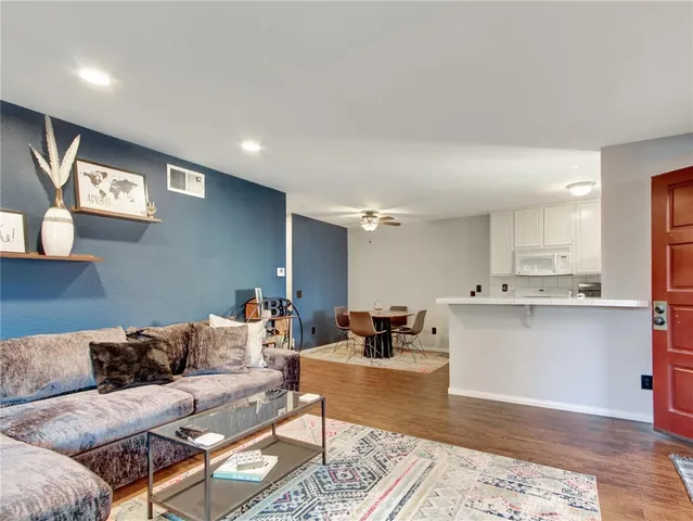 a living room with stainless steel appliances kitchen island granite countertop furniture wooden floor and a rug
