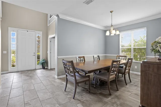a view of a dining room and livingroom with furniture wooden floor a chandelier and a rug