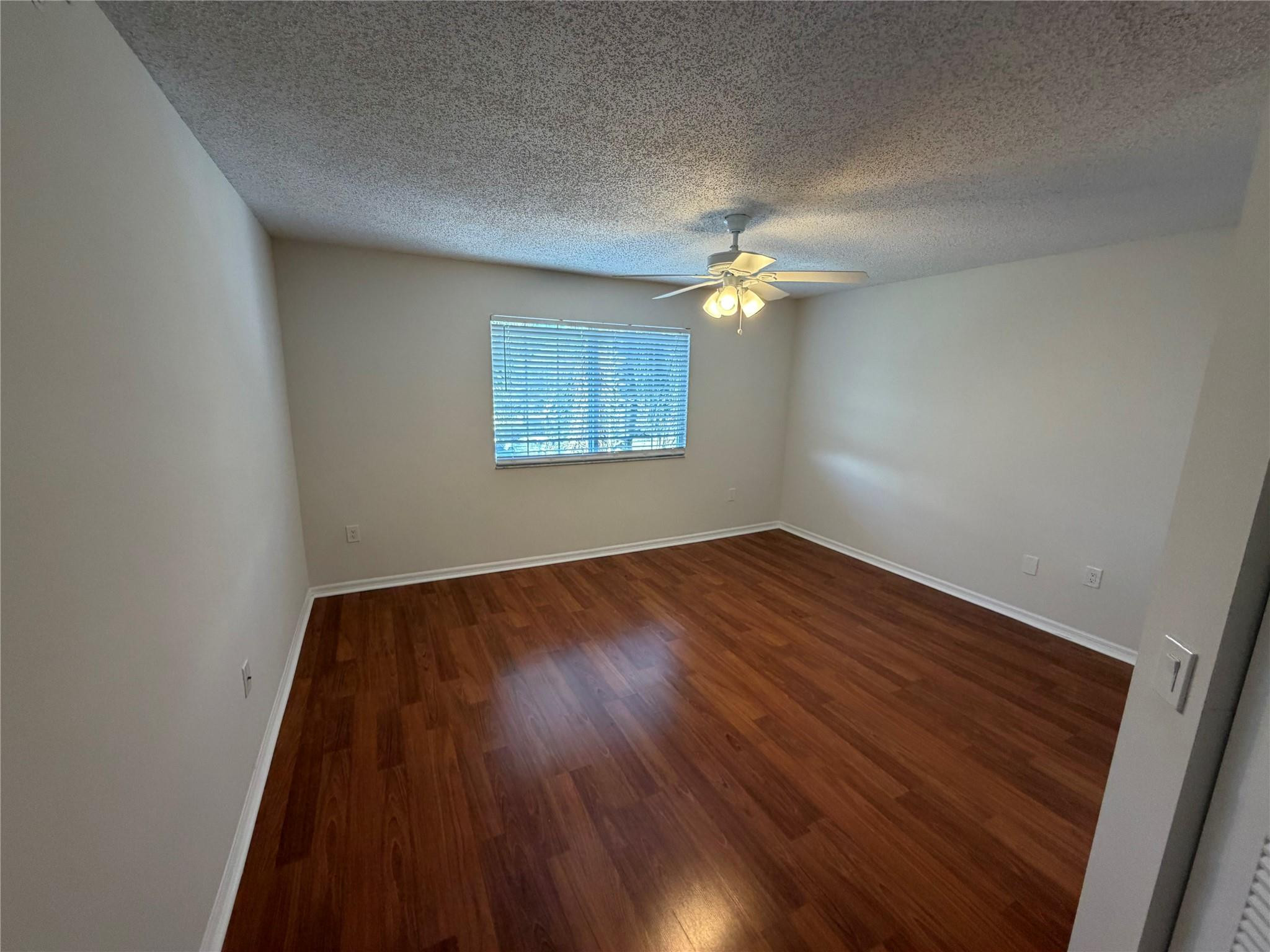 5005 Wiles Road, Unit 307 Pompano Beach, FL 33073 - Photo 11 of 28 an empty room with wooden floor fan and window