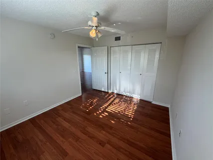 a view of a room with wooden floor and chandelier fan