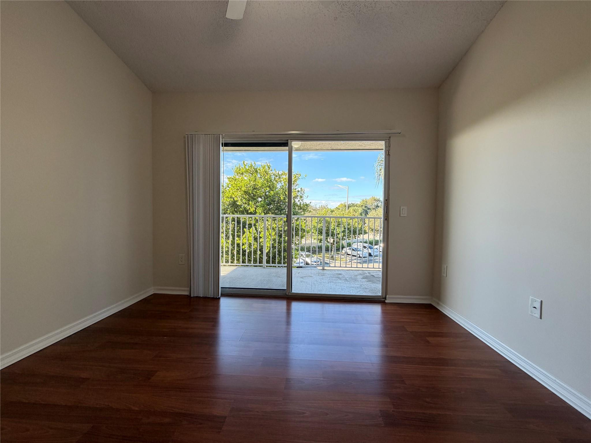 5005 Wiles Road, Unit 307 Pompano Beach, FL 33073 - Photo 19 of 28 a view of an empty room with wooden floor and a window