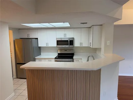 a kitchen with a sink a microwave a refrigerator and cabinets