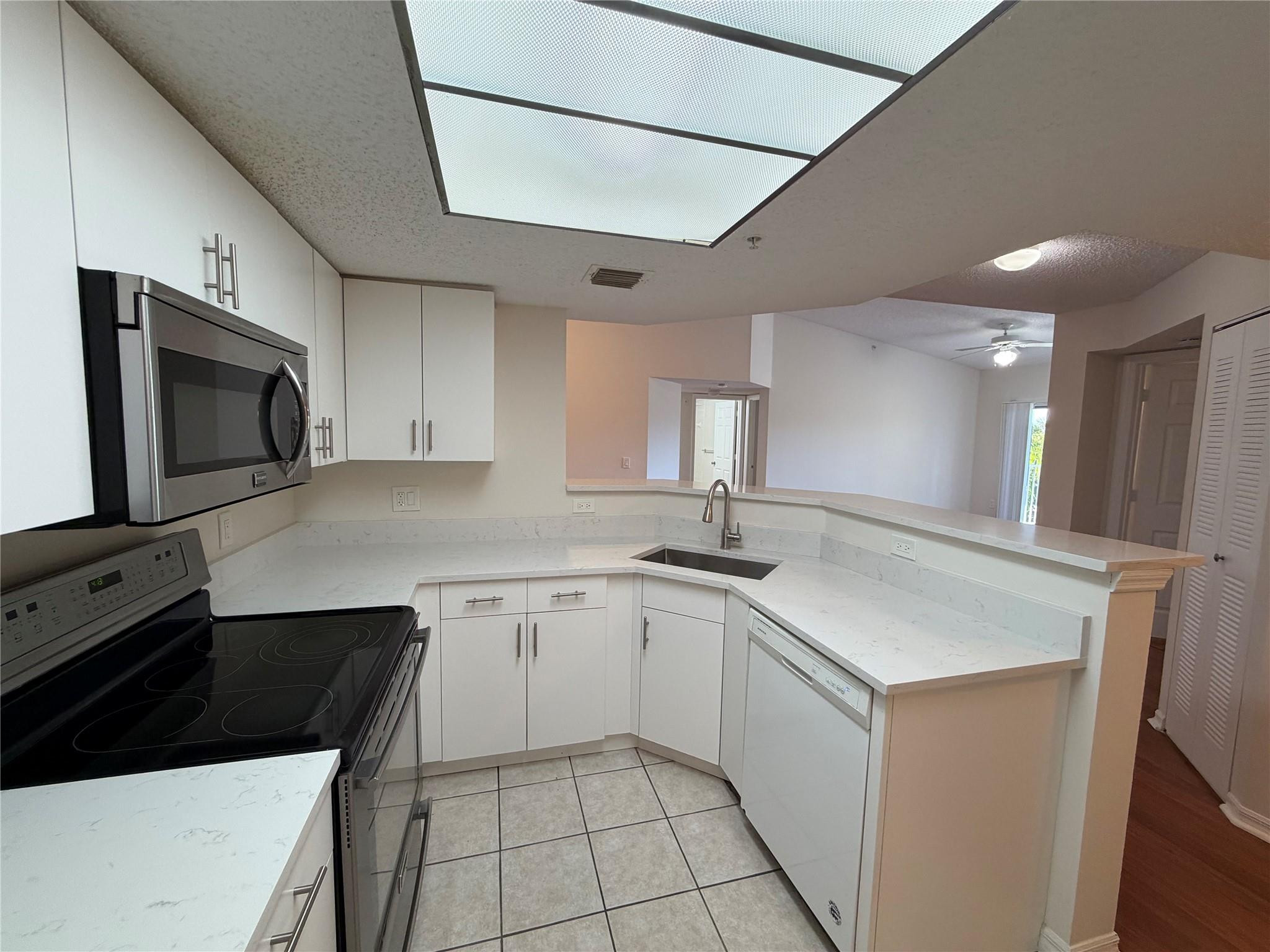 5005 Wiles Road, Unit 307 Pompano Beach, FL 33073 - Photo 9 of 28 a kitchen with a sink stove and microwave