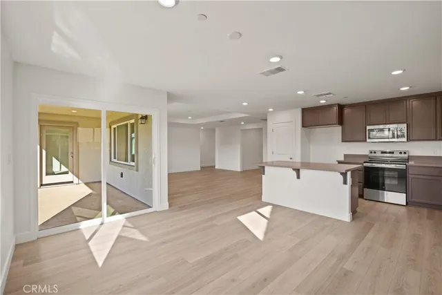 a large kitchen with a large counter top a sink stainless steel appliances and cabinets