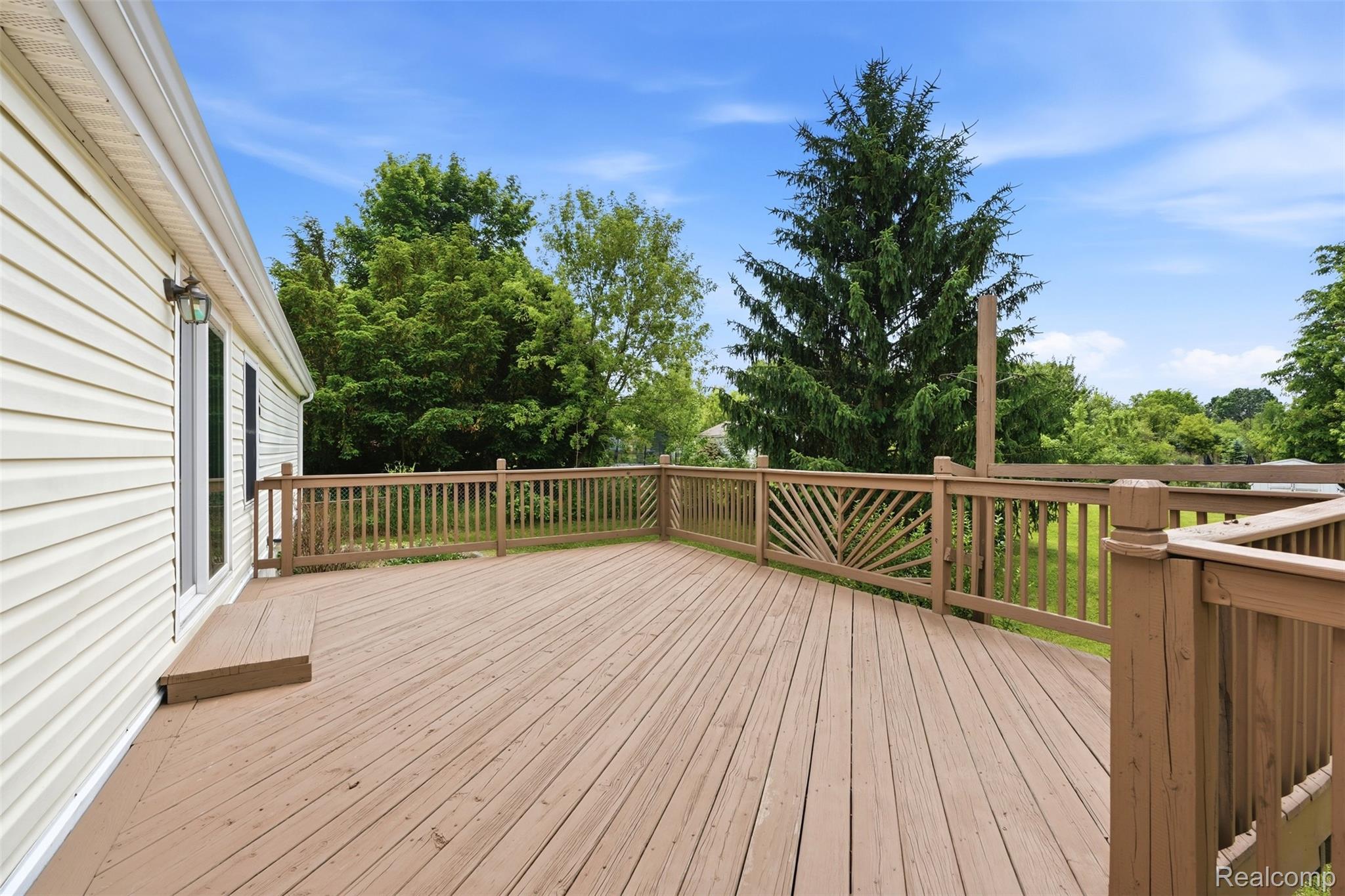 4420 Dublin Road Burton, MI 48529 - Photo 39 of 56 Expansive wood-finish deck with a sunburst-pattern railing detail, providing ample outdoor living space