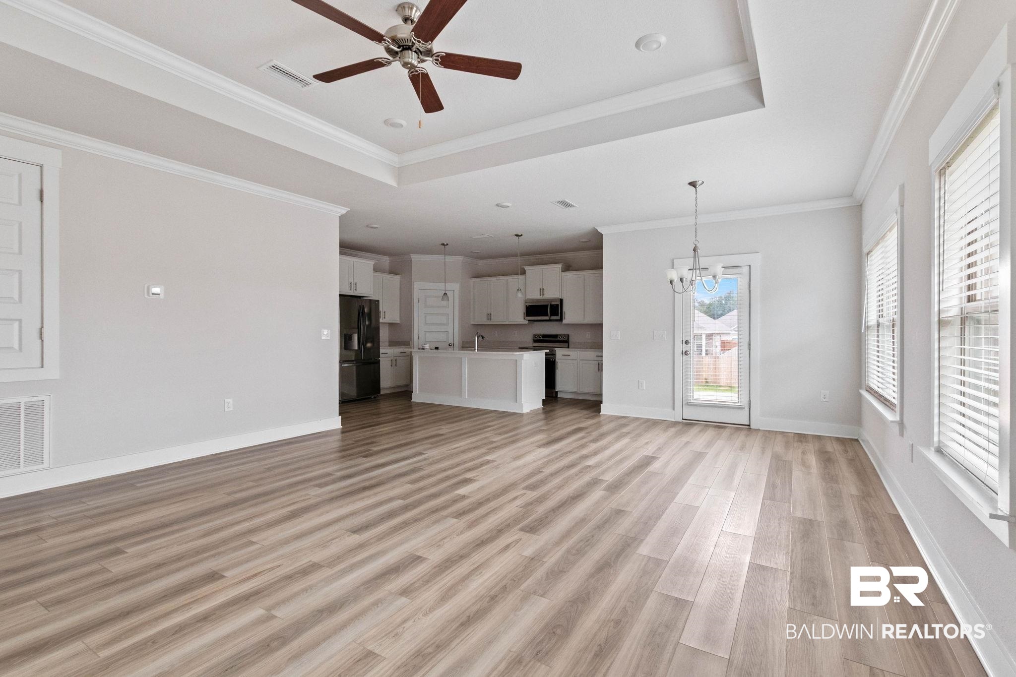 1710 Grouse Street Foley, AL 36535 - Photo 17 of 76 Spacious open-concept interior featuring light wood-finish flooring and a tray ceiling with a ceiling fan
