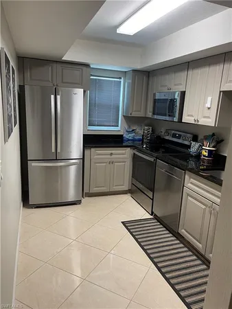 a kitchen with stainless steel appliances granite countertop a refrigerator sink and white cabinets