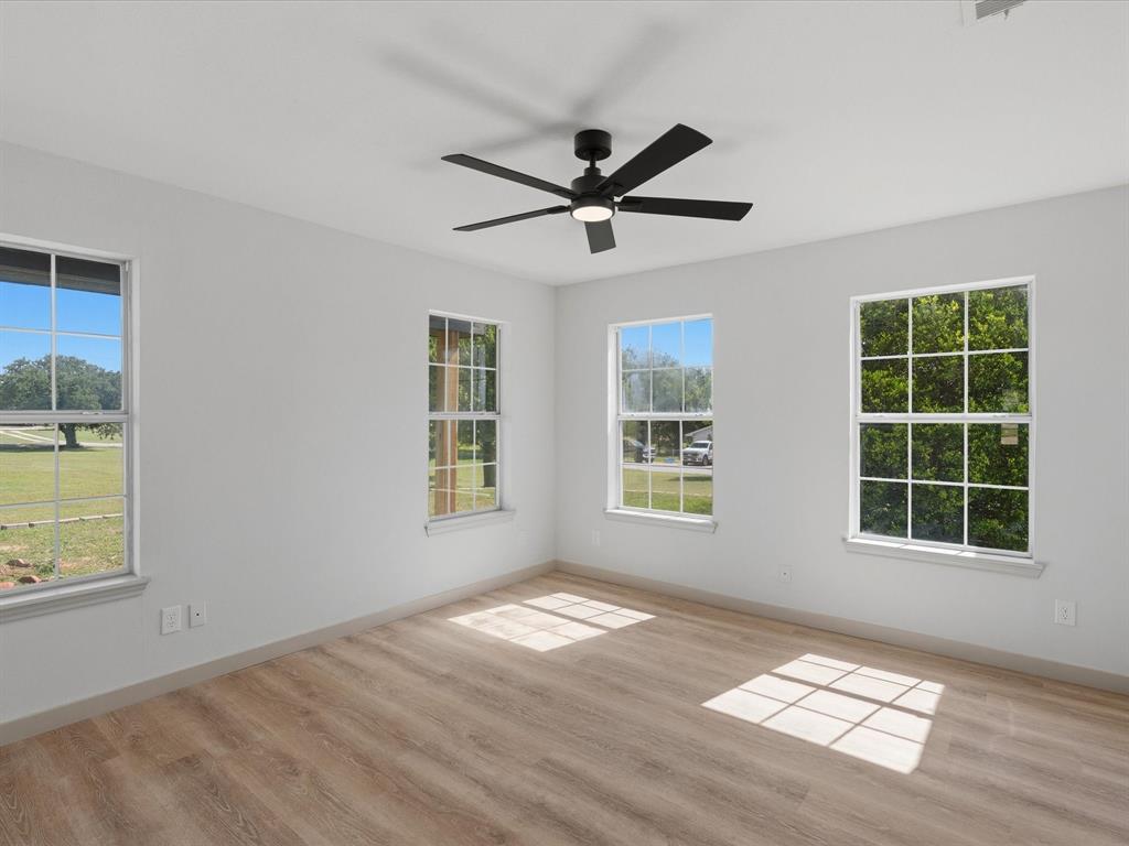 289 County Road 4655 Rhome, TX 76078 - Photo 15 of 34 Second bedroom with wood-finish flooring, light gray walls, and a contemporary black ceiling fan with integrated lighting