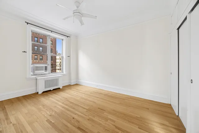 an empty room with wooden floor cabinet and windows
