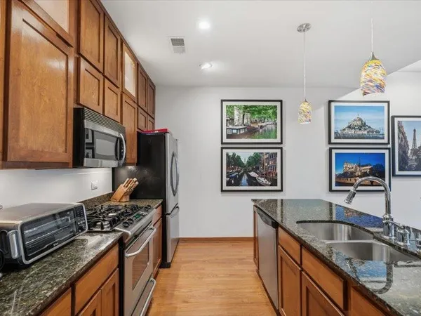 a kitchen with stainless steel appliances granite countertop a stove a sink and a refrigerator