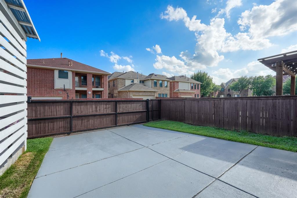 2246 Longview Road Irving, TX 75063 - Photo 40 of 40 Expansive paved patio area featuring a stained wood privacy fence, a strip of green lawn, and an overhead pergola structure