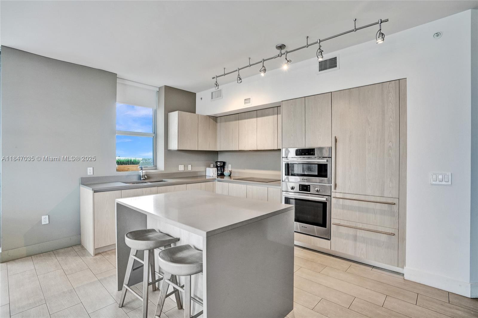 4010 South Ocean Drive, Unit R908 Hollywood, FL 33019 - Photo 11 of 53 a kitchen with kitchen island white cabinets and stainless steel appliances
