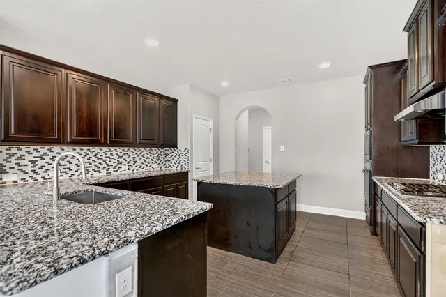 a kitchen with granite countertop a sink cabinets and stainless steel appliances