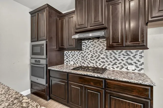 a kitchen with granite countertop stainless steel appliances and wooden cabinets