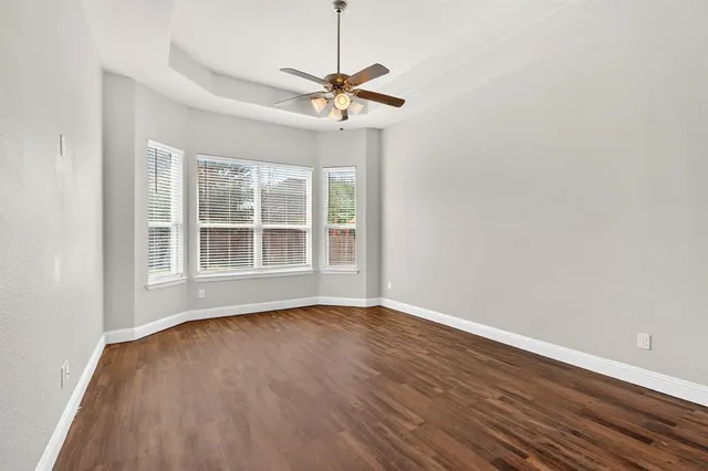 a view of a room with wooden floor fan and windows
