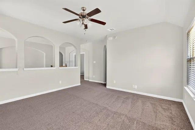 an empty room with chandelier fan and windows