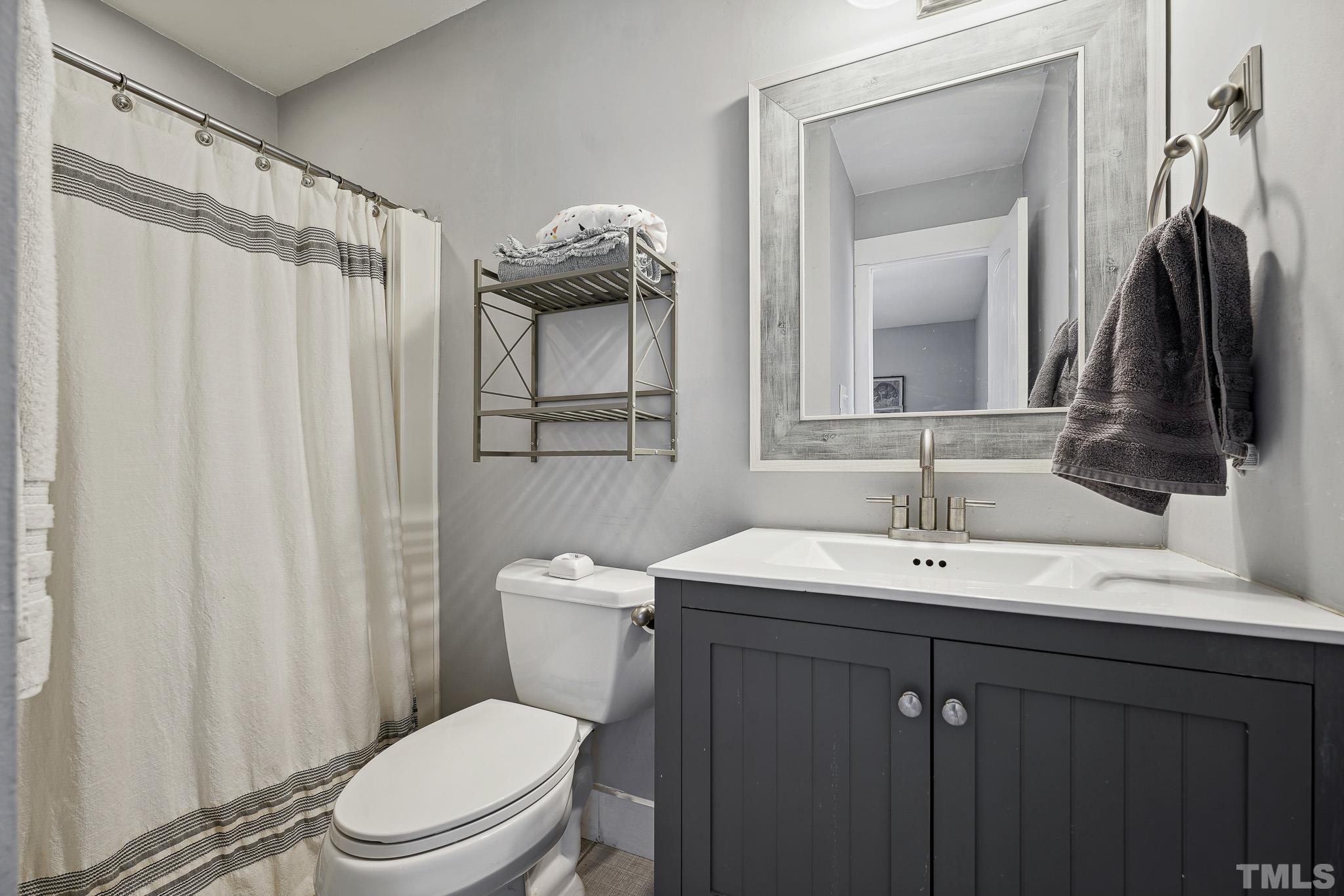 5218 Duraleigh Road Raleigh, NC 27612 - Photo 16 of 27 a bathroom with a toilet a sink and a mirror