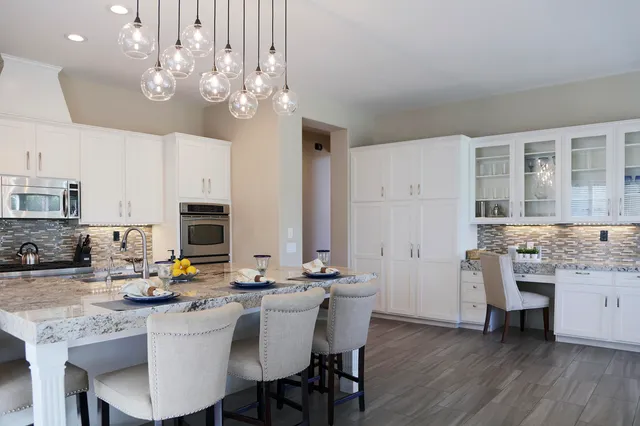 a kitchen with stainless steel appliances a table chairs and a refrigerator