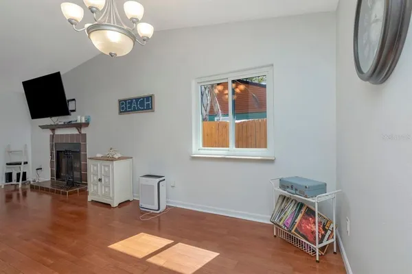 a room with chandelier fan and wooden floor