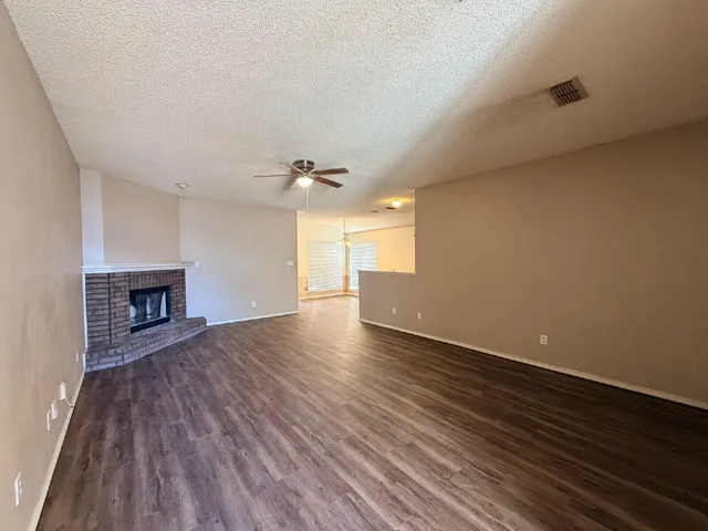 a view of an empty room with wooden floor and a fireplace