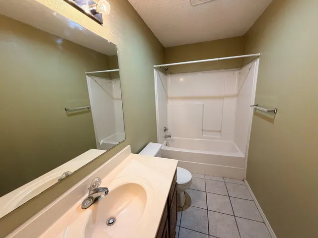 a bathroom with a granite countertop sink a toilet and shower
