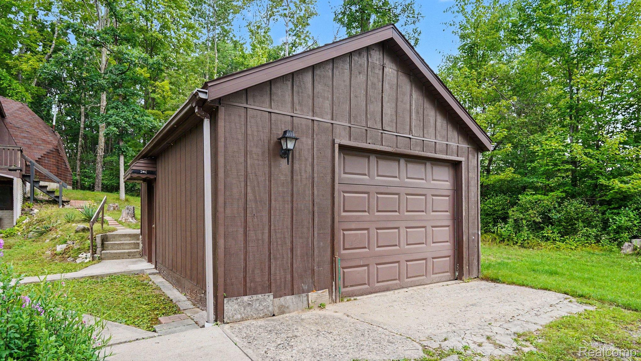 3700 Elbow Lake Road Prescott, MI 48756 - Photo 20 of 29 Detached garage with panel door, vertical board siding, exterior sconce, and a concrete driveway