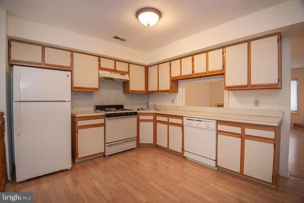a kitchen with granite countertop a refrigerator a sink and white cabinets